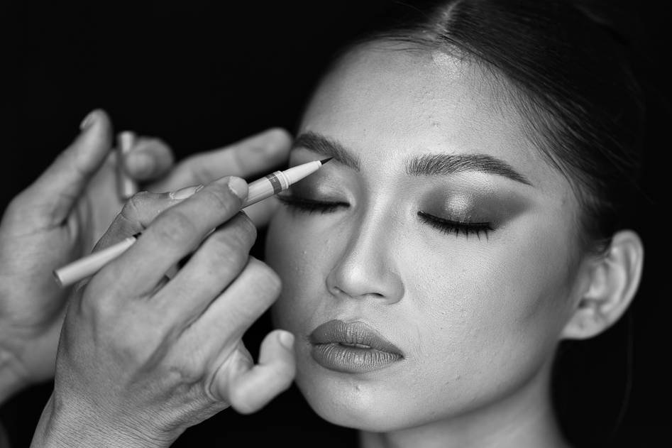 Runway makeup artist applying bold eyeshadow on a model backstage at a fashion show
