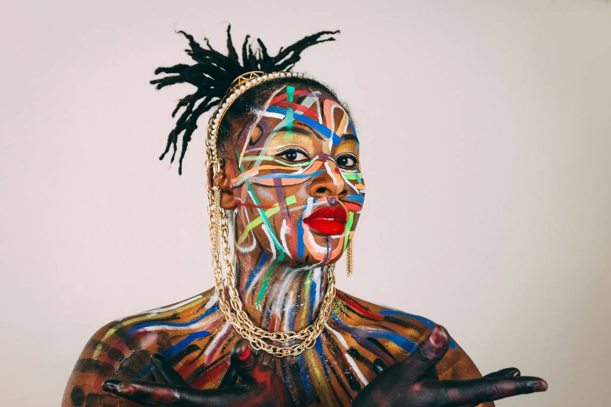 Model with geometric artistic face painting in bold red and silver lines on runway
