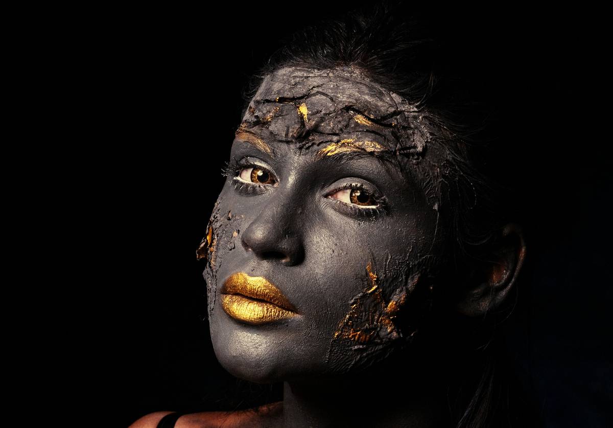 futuristic face makeup featuring iridescent silver eyelids, geometric black chrome temples, and matte gunmetal lips on a model with cool-toned olive skin